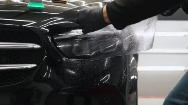 Siyah eldivenli bir çift elin arabanın farına ıslak film sürerken çekilmiş görüntüleri. Yüksek kalite 4k görüntü