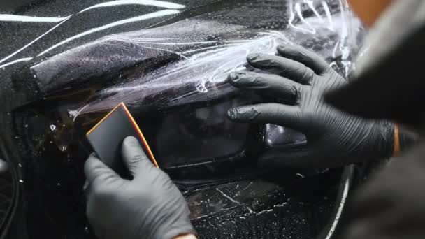 Εφαρμογή Προστατευτικής Μεμβράνης Ένα Μαύρο Αυτοκίνητο Παρά Τρίχα Σχέδιο Συντήρησης — Αρχείο Βίντεο