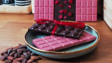 Pembe ve koyu çikolatalı. Tabağında kırmızı bir fiyonk ve ahşap bir masa var. Kamera dönmeye devam ediyor. Yüksek kalite 4k görüntü