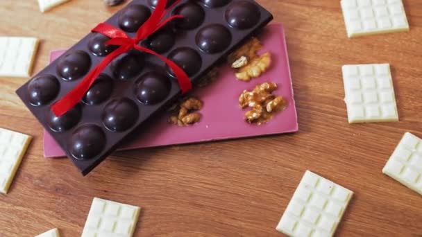 Rubinweiße Und Dunkle Schokoladentafel Mit Roter Schleife Auf Einem Teller — Stockvideo
