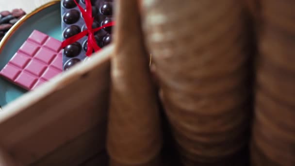 粉红色和深色巧克力条 红色的弓在盘子里 坚果在木制桌子上 高质量的4K镜头 — 图库视频影像