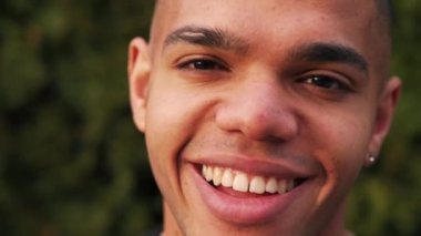 Neşeli Afro-Amerikalı genç adam geniş gülümsemeli ve sokakta ürpertici, yakın çekim. Yüksek kalite 4k görüntü