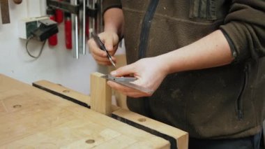 Bir marangozun elleri ahşap bir tahta üzerine işaretleyici ve cetvel kullanarak dikkatle çizgiler çiziyor. Yüksek kalite 4k görüntü