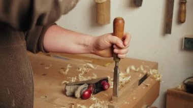 Marangoz, marangoz tezgahına tahta oymak için keski ve çekiç kullanıyor. Yavaş çekim. Yüksek kalite 4k görüntü