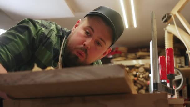 Skupiony Stolarz Wysadzający Wióry Drewna Drewnianej Deski Warsztacie Wysokiej Jakości — Wideo stockowe