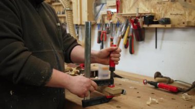 Marangoz ahşap parçaları yapıştırdıktan sonra onları birleştirmek için bir bar kıskacı kullanır. Yüksek kalite 4K görüntü