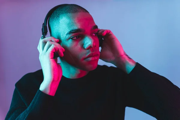 stock image Afro-American young man with headphones listening to the music and relaxing, blue background. High quality photo