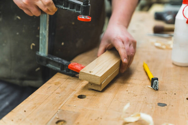 carpenter putting a wooden plank on a pressing tool, handicraft concept. High quality photo