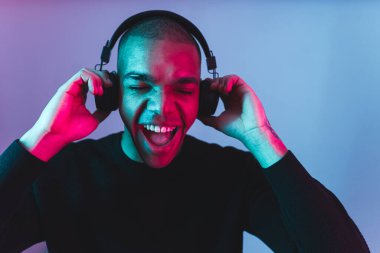 Heyecanlı Afro-Amerikan erkek manken kulaklık stüdyo çekimi kullanarak müzik dinliyor. Yüksek kaliteli fotoğraf.