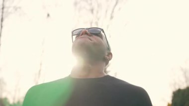 Siyah tişörtlü, güneş gözlüklü açık hava manzaralı neşeli erkek model. Yüksek kalite 4k görüntü