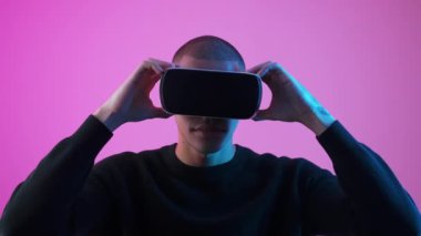 Video kaset izleyen siyah erkek manken hayrete düştü. Stüdyo çekimi pembe arka planda izole edildi. Yüksek kalite 4k görüntü