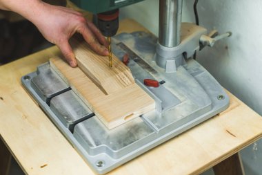 Marangozların avuçlarını yakın plan çekimde, tahta bir parça üzerinde çalışmak için elektrikli matkap yerleştirirken. Yüksek kalite fotoğraf