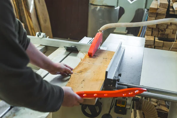 Carpenter using table saw blade to cut wooden plank while sliding it on a table. High quality photo