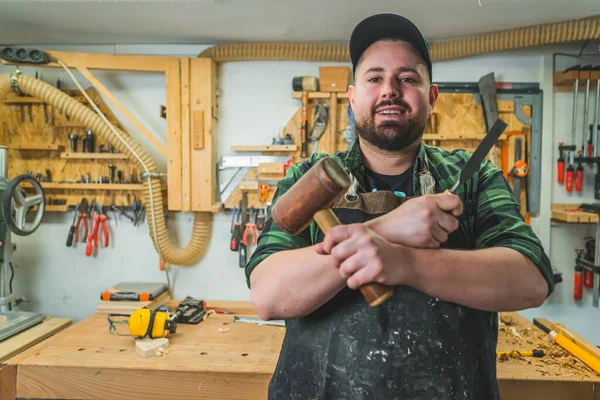 stock image Portrait of confident carpenter holding hammer and chisel in woodworking studio. High quality photo