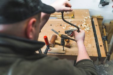 Erkek bir marangozun, arka planda diğer aletlerle birlikte tahta bir kalasta delik açarken yakın plan çekimi. Yüksek kalite fotoğraf