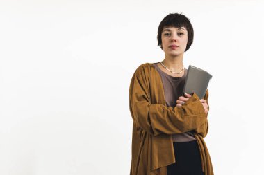 Yüzünde ciddi bir ifade olan ve elinde bir dosya tutan kısa saçlı bir kadının orta boy fotoğrafı. Yüksek kalite fotoğraf