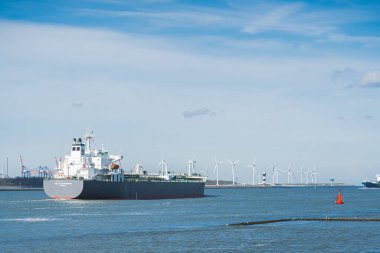 Güneşli bir havada Avrupa 'nın en büyük limanı olan Maasvlakte Rotterdam' dan kalkan büyük bir gemi. Rüzgar enerji türbinleri. Yüksek kalite fotoğraf