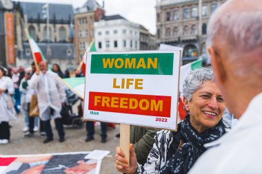 04.18.2023 Amsterdam, Hollanda. Posterli, kısa saçlı kadın protestocu. Kadın, yaşam, özgürlük. İran bayrağı renkleriyle yapılmış. Yüksek kalite fotoğraf
