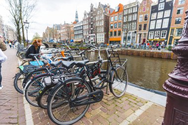 Klasik Amsterdam manzarası. Kanalın yanında bir sürü bisiklet yan yana duruyor. Açık hava çekimi. Hava bulutlu. Yüksek kalite fotoğraf
