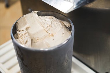 Dondurucunun yakın çekiminden yeni hazırlanmış çelik kapta vanilyalı dondurma. Yüksek kalite fotoğraf