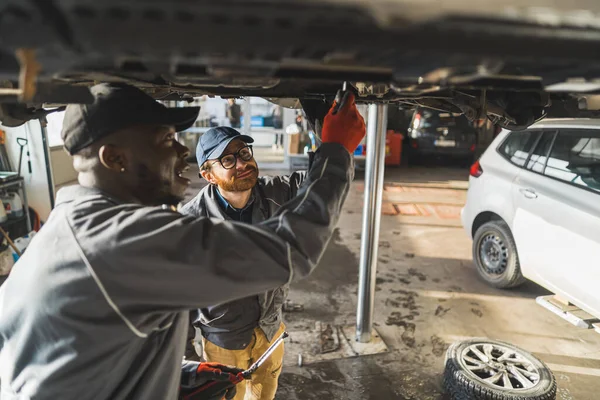 Two Male Auto Mechanics Working Car Lift Service Shop High — Stock Photo, Image