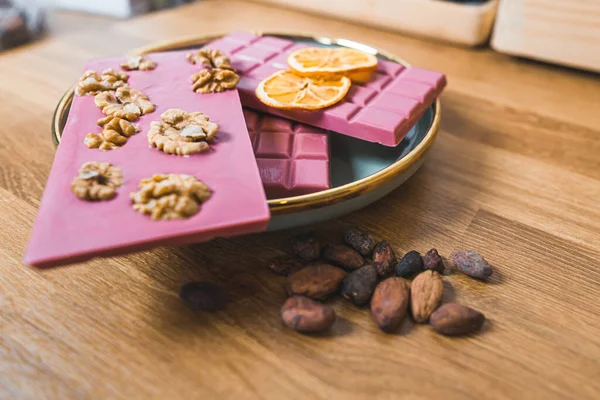 Ruby dark and white chocolate bars with orange slices and cacao seeds on a table. High quality photo