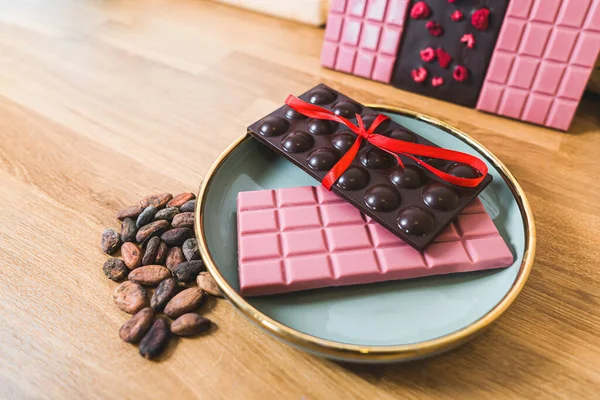 Ruby white and dark chocolate bar with bow on plate fruit and nuts chocolate bar. High quality photo