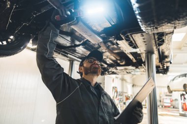 Tamirci tamircide asansörle arabanın altını inceliyor. Yüksek kalite fotoğraf