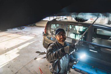 Gülümseyen araba tamircisi bir arabanın şasisi üzerinde çalışıyor. Yüksek kalite fotoğraf