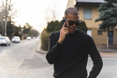 Afrika kökenli Amerikalı bir adam gündüz vakti sessiz bir sokakta evinin önünde nöbet tutuyor. Yüksek kalite fotoğraf