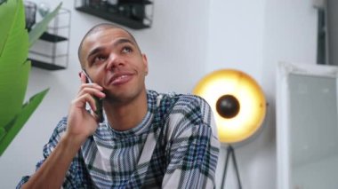 Erkek içerikli yaratıcı, arka planda bir lambayla kendi stüdyosundaki akıllı telefonu kullanarak konuşuyor. Yüksek kalite 4k görüntü