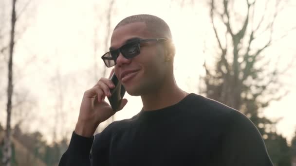 サングラスの黒男の友人に電話でスマートフォンを使用して話して 高品質4K映像 — ストック動画