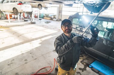 Araba tamircisi kaldırılmış bir arabanın şasisi üzerinde çalışıyor. Yüksek kalite fotoğraf