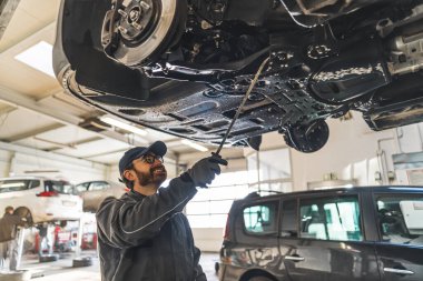 Erkek tamirci altında dururken arabayı tamir ediyormuş. Yüksek kalite fotoğraf