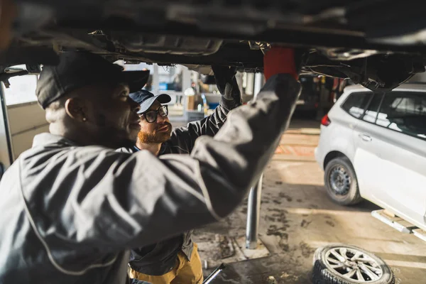 Två Unga Bilservicearbetare Kontrollerar Bilens Fjädring Hydraulisk Lyft Högkvalitativt Foto — Stockfoto