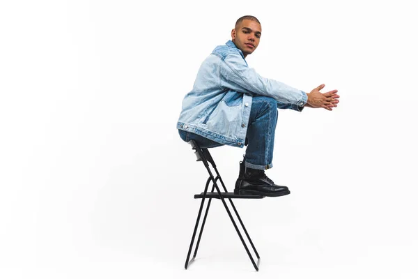 Junger Schwarzer Kerl Jeanskleidung Sitzt Auf Einem Stuhl Vor Weißem — Stockfoto