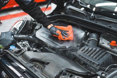 Bir araba motorunun derin buhar temizliğinin yakın çekimi. Koruyucu siyah eldivenli bir adam mikrofiber turuncu bezle motoru kurutuyor. Yüksek kalite fotoğraf