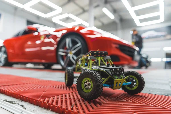 おもちゃの車とスポーツカーの比較 本物の豪華な赤いスポーツカーの前でオフローダーおもちゃの車 交通と趣味 高品質の写真 — ストック写真