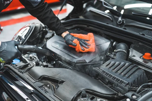 闭塞拍摄的蒸汽深入清洗汽车发动机 戴着黑色防护手套的男人用微纤维橙色布擦干发动机 高质量的照片 — 图库照片