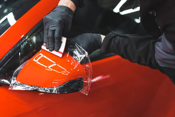 Процесс установки PPF на боковое зеркало красного спортивного автомобиля. Защитная пленка для защиты от царапин и гравия. Высокое качество фото