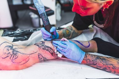 Profesyonel bir dövme sanatçısı, bir kadının bacağına mürekkeple siyah beyaz dövme yapar. Derinin dövmesini yaptırma süreci. Yüksek kalite fotoğraf
