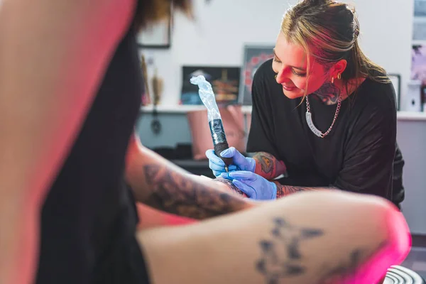 tattoo artist girl drawing a new tattoo and talking to her client, medium shot. High quality photo