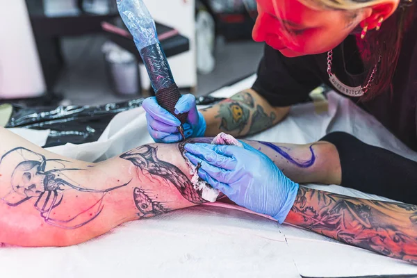 一名专业纹身艺术家用墨水在女人的腿上做一个黑白纹身 在皮肤上纹身的过程 高质量的照片 — 图库照片