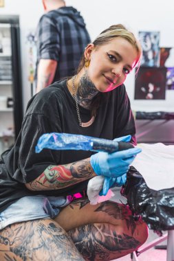 Sanat stüdyosunda çalışan genç ve güzel bir dövme ustasının orta boy fotoğrafı. Dövme konsepti. Yüksek kalite fotoğraf