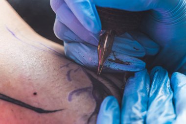 Dövme ustası elleri ve eldivenleri dövme üzerinde çalışırken yakın çekim. Yüksek kalite fotoğraf