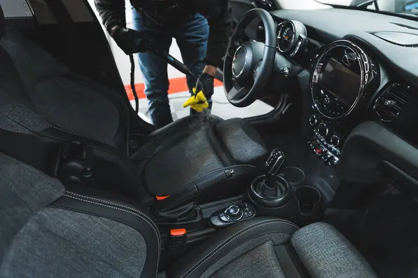 黒い車の内装を掃除する男 クリーンな車の座席に熱いストリーミングマシンを準備するスタジオワーカーを詳述車 高品質の写真 — ストック写真