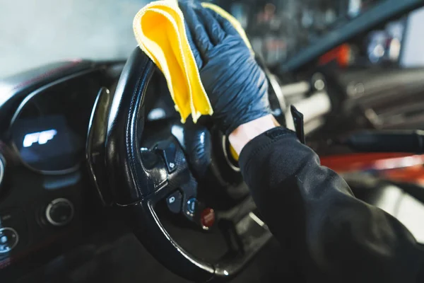 在汽车的详细设计过程中 一只手戴着黑色手套 手拿着橙色的微纤维布擦拭方向盘 拍下了一张合影 高质量的照片 — 图库照片
