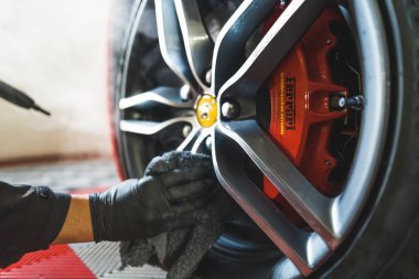 05.17.2023 Varşova, Polonya. Araba tekerleklerini ve lastikleri buharlı kapakla dezenfekte ediyor. Erkek araba temizleme uzmanı Ferrari tekerleğini kurutuyor. Yüksek kalite fotoğraf