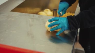 Closeup shot of skilled professional slicing raw peeled celery roots on steel counter and placing them in big red box. Hands carefully operating a kitchen knife. High quality 4k footage