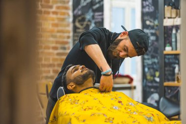 Barber trimming the neck hair of a client using a hair clipper in a modern salon. High quality photo